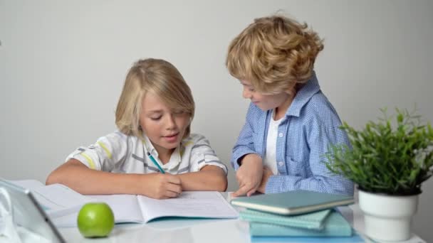 Primary elementary middle school boy girl siblings studying at desk table, writing in book and tablet at class home homework acquiring information knowledge Back to school. - Footage, Video