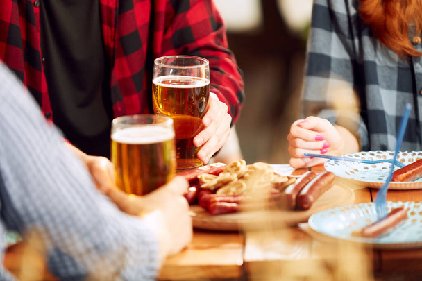 People, friends meeting at pub, restaurant to drink beer. Glasses with foamy lager beer and appetizers with sausages. Concept of oktoberfest, traditional taste, friendship, leisure time, enjoyment - Foto, Imagem