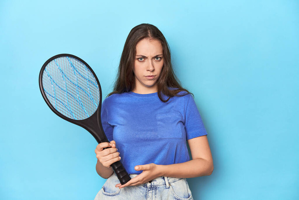 Frau hält in einem blauen Studio einen elektrischen Mückenzapper in der Hand. - Foto, Bild