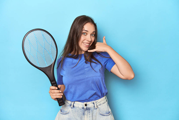 Frau mit einem elektrischen Käfer-Zapper auf blauem Hintergrund, der eine Handygeste mit den Fingern zeigt. - Foto, Bild