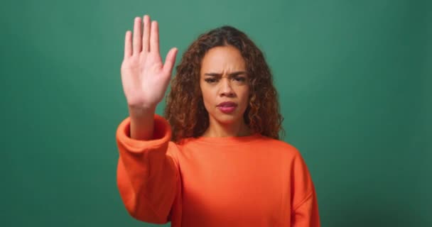Молода багатоетнічна жінка тримає руку, кажучи "Ні, зупиніться, зелений студійний фон". Високоякісні 4k кадри - Кадри, відео