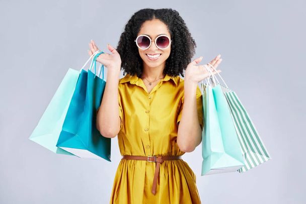 Sonnenbrille, Porträt und glückliche Frau mit Einkaufstasche für Mode im Studio isoliert auf weißem Hintergrund. Cool, Verkauf und afrikanischen Kunden mit Geschenk, Rabatt-Deal und stilvolle Kleidung aus dem Geschäft. - Foto, Bild