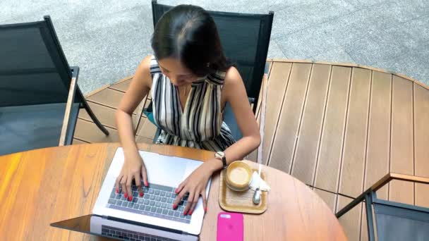 Asyalı kadın iyi giyimli restoranda kahve içiyor dizüstü bilgisayarla çalışıyor.. - Video, Çekim