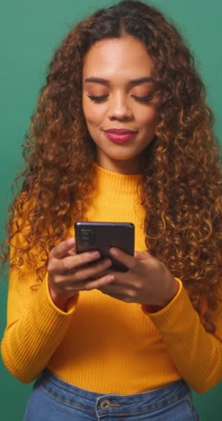 Mujer birracial joven lee mensaje de texto conmocionado emocionado, fondo de estudio verde. Imágenes de alta calidad 4k - Metraje, vídeo