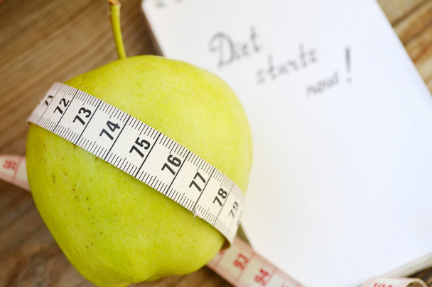 Concepto de dieta con manzana verde, un cuaderno y una cinta métrica en la mesa de madera
 - Foto, Imagen