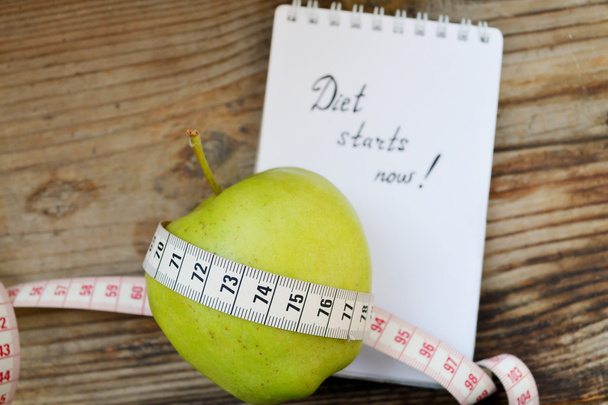 Concetto di dieta con mela verde, un quaderno e un metro su tavolo di legno
 - Foto, immagini