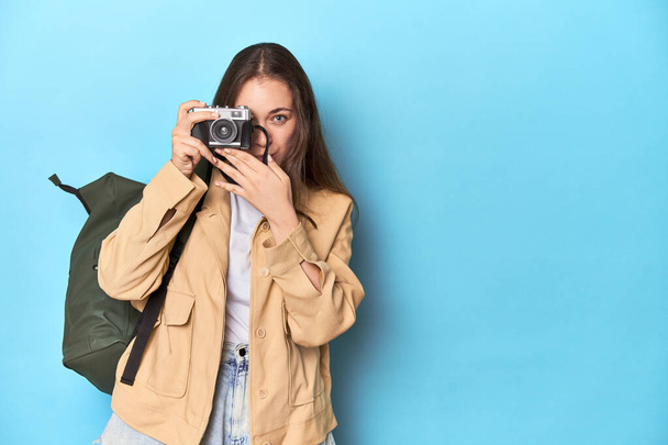 Ταξιδεύοντας γυναίκα τραβώντας φωτογραφίες με μια vintage κάμερα στο μπλε. - Φωτογραφία, εικόνα