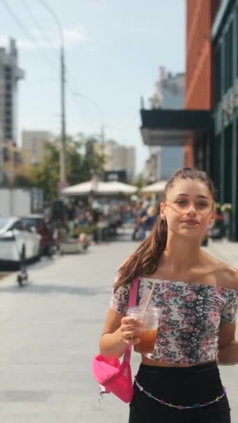 Eine stylische, lebendige junge Frau auf den Straßen der Stadt mit einem kalten Kaffee und einem Smartphone in der Hand. Hochwertiges 4k Filmmaterial - Filmmaterial, Video