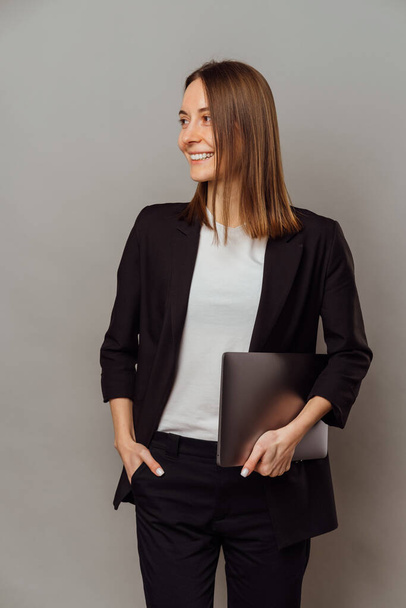 Vertikale Foto der jungen Frau in lässig über grauen Hintergrund hält Laptop. - Foto, Bild