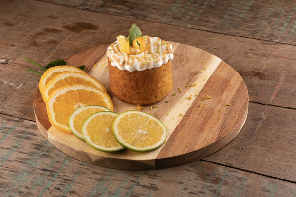 bolo de laranja com creme branco tostado em cima da mesa de madeira rústica no bistrô com fatias de laranja de ângulo verde e amarelo - Foto, Imagem