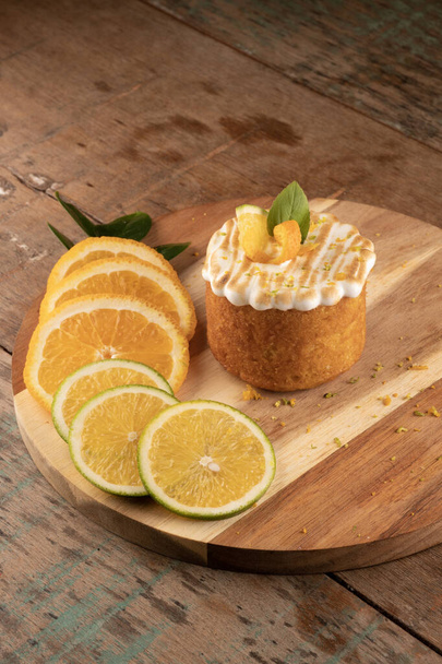 narancs torta pirított fehér krém tetején rusztikus fa asztal bisztró narancs szeletek szög nézet - Fotó, kép