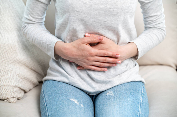 腹部に触れる女性のクロップビュー. 胃,月経痛,腹腔炎または胃腸疾患の不快感を感じる - 写真・画像