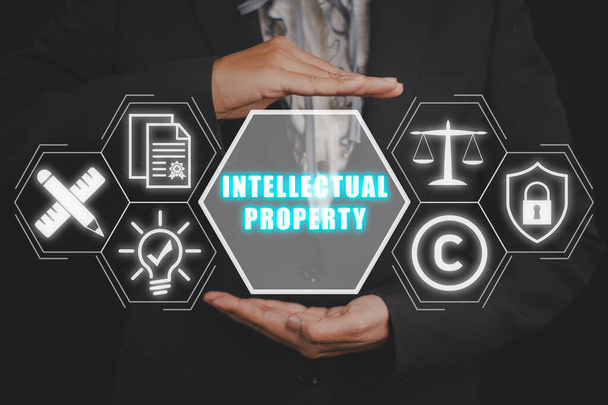 Intellectual property concept, Businesswoman hand holding intellectual property icon on virtual screen. - Photo, Image