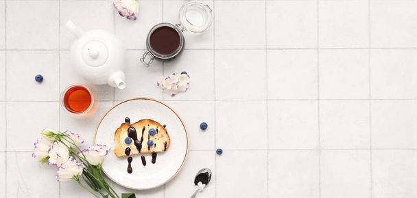 Teller mit süßem Blaubeermarmelade-Toast und Tee auf weißem Kacheltisch. Banner für Design - Foto, Bild