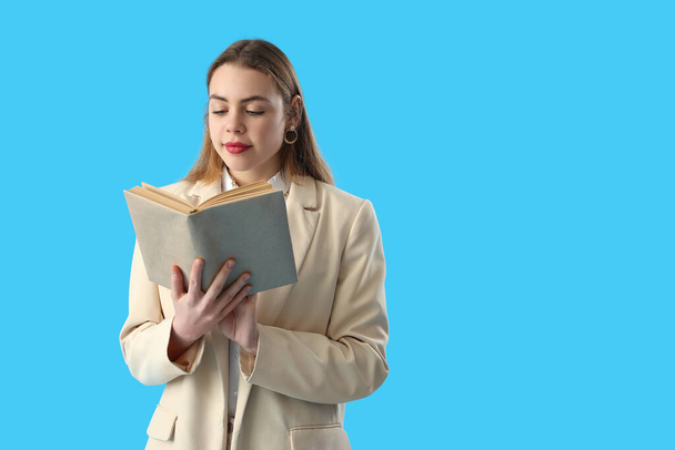 Молода жінка читає книгу на синьому фоні
 - Фото, зображення