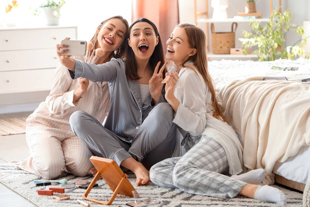 Nuoret naiset soveltava meikki ottaen selfie makuuhuoneessa - Valokuva, kuva