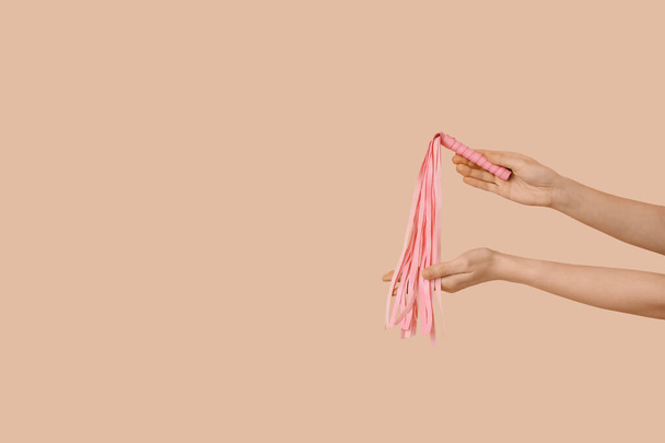 Woman with pink whip from sex shop on beige background - Фото, зображення