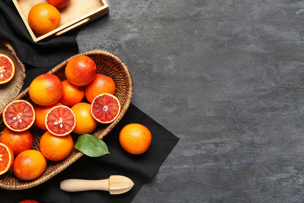Panier en osier avec de savoureuses oranges sanguines sur fond sombre - Photo, image
