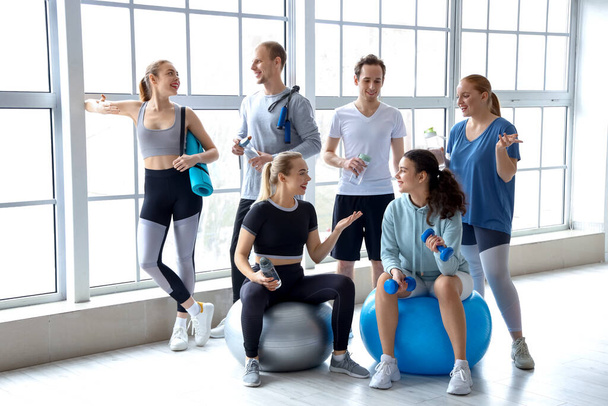Group of sporty young people with bottles of water and equipment in gym - Fotografie, Obrázek