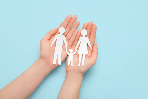 Woman holding human figures on blue background. Family love concept - Foto, Bild