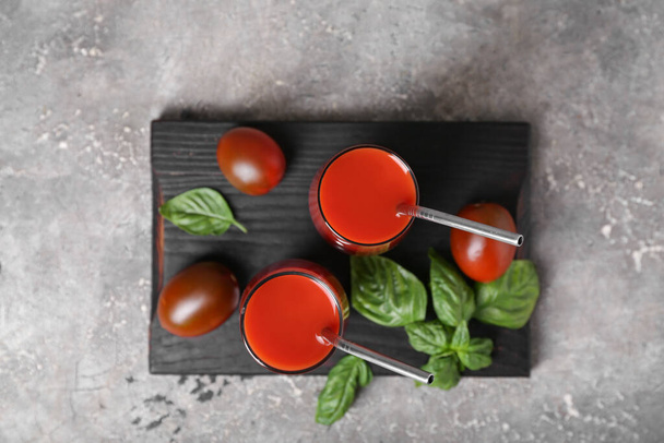 Vasos de sabroso jugo de tomate sobre fondo gris - Foto, Imagen