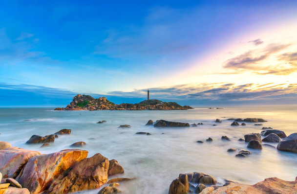 Landscape of the small island with the ancient lighthouse at sunset sky is beautiful and peaceful. This is the only ancient lighthouse is located on the island in Vietnam - Photo, image