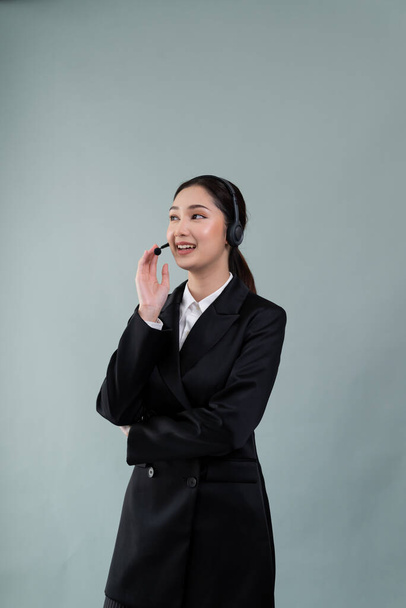 Atractivo asiático operador de centro de llamadas femenino con la cara sonrisa feliz anuncia la oportunidad de trabajo en el espacio vacío, con un traje formal y auriculares en fondo aislado personalizable. Entusiasta. - Foto, imagen