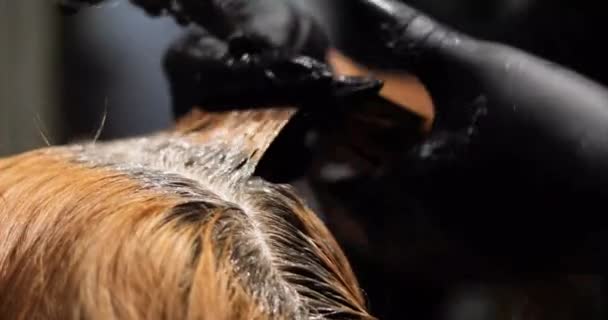 barbeshoper in guanti applica una maschera rianimante con carotene vegetale e vernice a capelli tinti indeboliti. Cura e trattamento dei capelli - Filmati, video