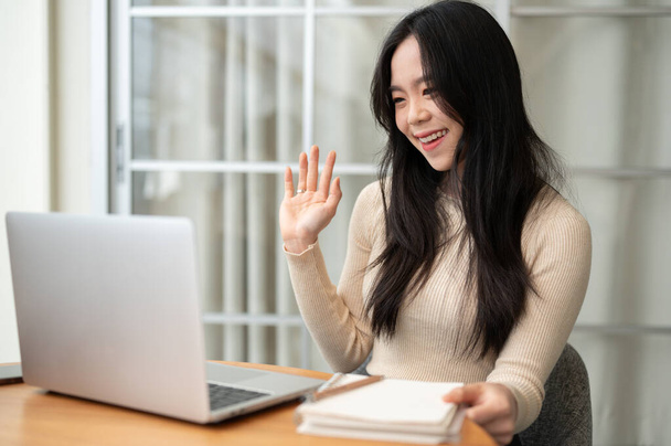 Onnellinen ja kaunis nuori aasialainen naisopiskelija opiskelee verkossa online-luokassa oleskellessaan kotona. - Valokuva, kuva