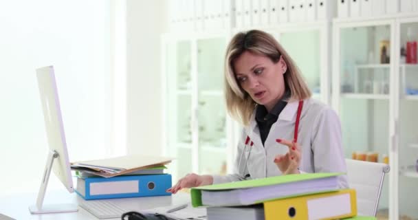 Unzufriedene Ärztin untersucht medizinische Dokumente in Klinik. Überstunden des Arztes im Krankenhaus - Filmmaterial, Video