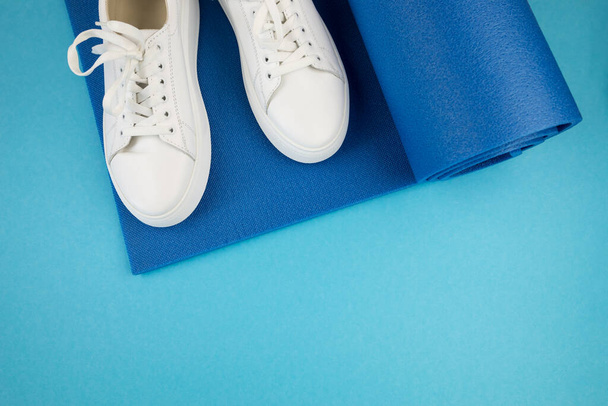 Top view photo of white sneakers and fitness mat. The concept of sport, yoga, fitness. - Photo, Image