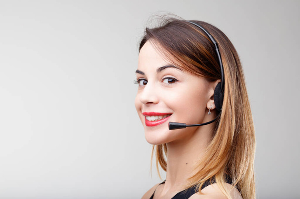 Eine junge Frau mit einem professionellen Headset, einer mehrsprachigen menschlichen Assistentin, kommuniziert mit ihren Kunden höflich und professionell. Die Stimme Ihres Unternehmens wird Experten wie ihr anvertraut - Foto, Bild