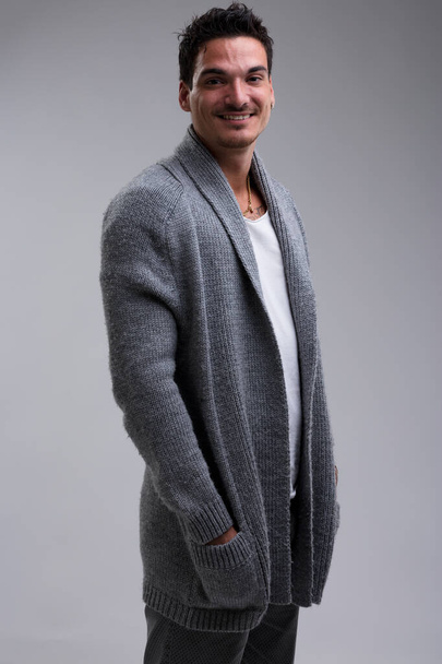 Handsome young man, tall, with short black hair, slight mustache, and light beard. He's laughing, wearing a wool jacket over a white t-shirt. Muscular, tanned, and confident - Photo, Image