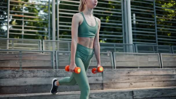 fit sexy flexibel meisje oefenen omgekeerde lunges met halters buiten - Video