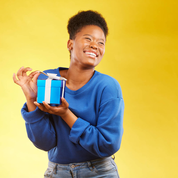 Gift, winning and happy black woman with a surprise isolated in a yellow studio background for a birthday. Giveaway, box and excited person to celebrate, party and holiday as a winner with happiness. - Foto, imagen