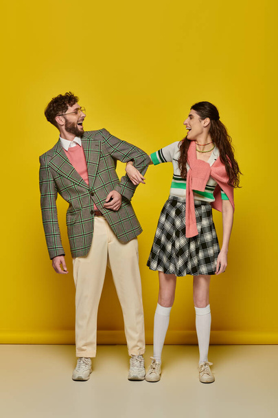 funny students, couple standing on yellow backdrop, open mouth, college outfits, academic wear - Foto, immagini