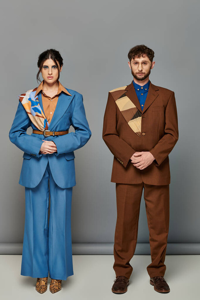 man en vrouw met baard, pakken op maat, poseren op grijze achtergrond, bruin, blauw, fashion shoot, koppel - Foto, afbeelding