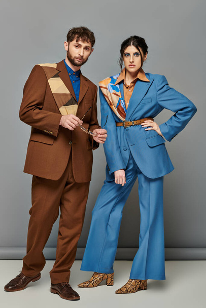 Paar und Mode, Models posieren in formeller Kleidung, blicken in die Kamera, grauer Hintergrund, elegante Anzüge - Foto, Bild