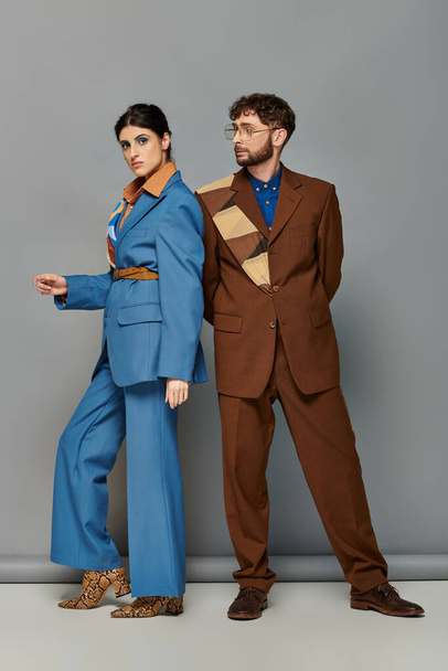 modelos de moda en trajes a medida posando sobre fondo gris, hombre y mujer en traje formal, elegante - Foto, Imagen