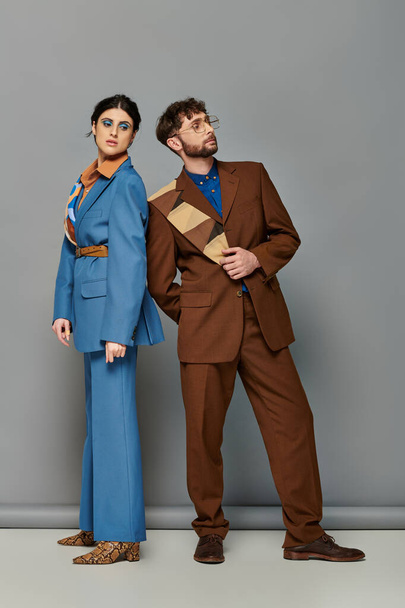 Models in Anzügen posieren auf grauem Hintergrund, Mann und Frau in maßgeschneiderter formaler Kleidung, elegant - Foto, Bild