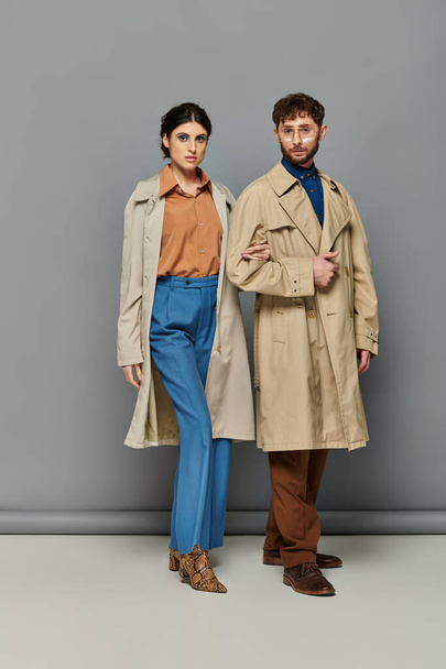 stylish couple in trench coats, fashion shot, man and woman, outerwear, grey background, trends - Foto, afbeelding