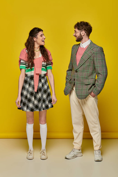 positive students looking at each other on yellow backdrop, happy man and woman in college outfits - Valokuva, kuva