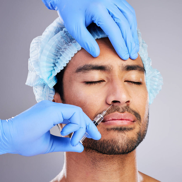 Hands, facelift and plastic surgery with a man in studio on a gray background for a botox injection. Face, change and transformation with a male customer in a clinic for beauty or antiaging filler. - Photo, Image