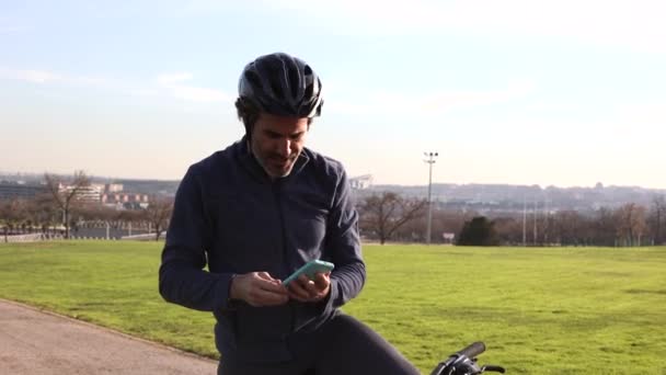 kypsä mies polkupyörällä tekee urheilua ottaa valokuvan älypuhelimella - Materiaali, video