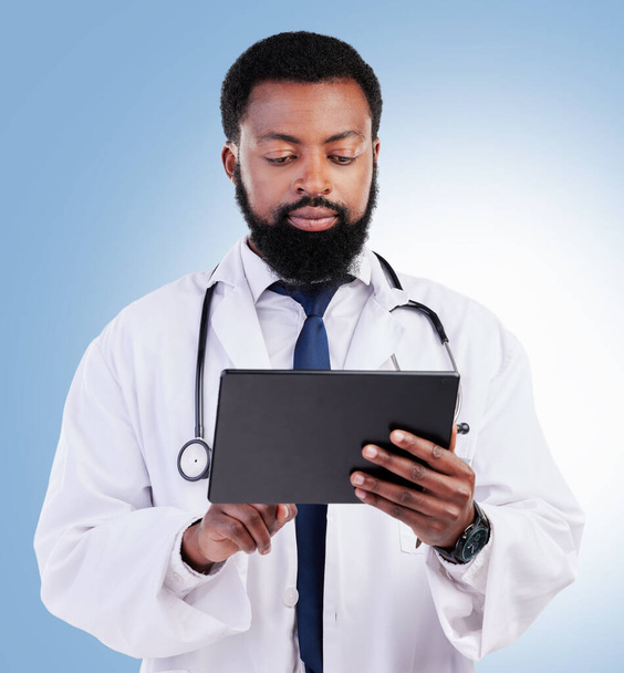 Gesundheitswesen, Tablette und ein schwarzer Arzt im Studio auf blauem Hintergrund für kardiologische Forschung. Medizin, Technologie und Innovation mit einem männlichen Mediziner auf der Suche nach Informationen im Internet. - Foto, Bild