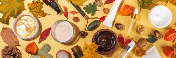 Stel verschillende voedende hydraterende anti-aging herfst gezichtsverzorging cosmetica. Serumfles, crème, scrub, biologische schoonheidsverzorging met herfstbladeren, decor, warme trui, op goudgele achtergrond - Foto, afbeelding
