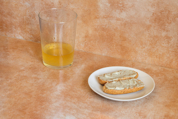 A small plate with two whole wheat toast with cream of Cabrales cheese with cider near a glass of cider with a shot of cider on an abstract studio background. A delicious and typical Spanish snack. - Photo, Image
