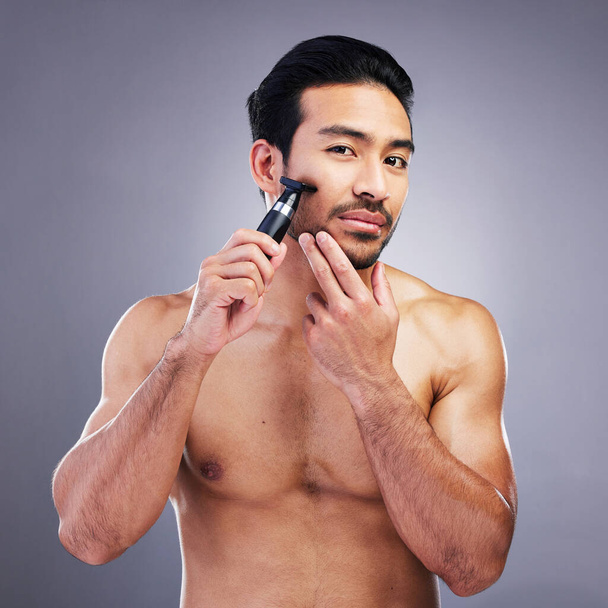 Beard hair, trimmer and portrait of man with bathroom routine, wellness grooming and cosmetics skincare. Morning face cleaning, facial growth maintenance and studio person shaving on grey background. - Foto, Imagem