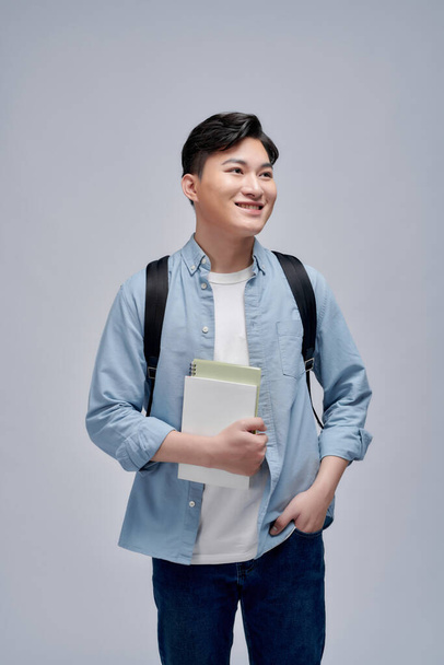  retrato de un joven sonriente vestido con una mochila aislada, sosteniendo libros - Foto, Imagen