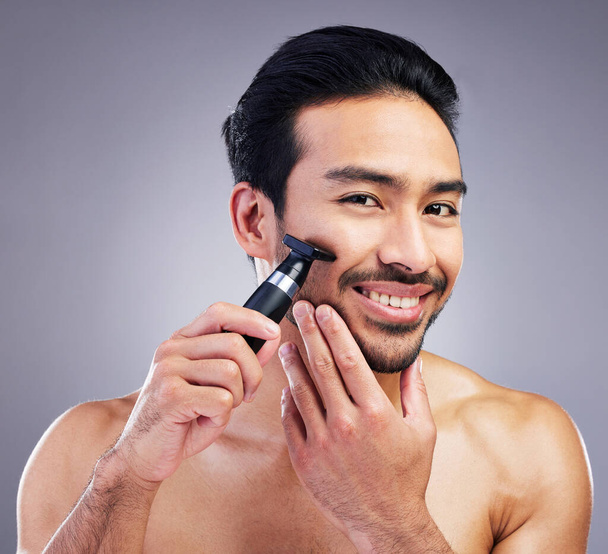 Beard hair trimmer, portrait and man smile for bathroom shaving routine, grooming or morning skincare. Studio razor, facial growth maintenance and Mexican person with clean face on gray background. - Photo, Image